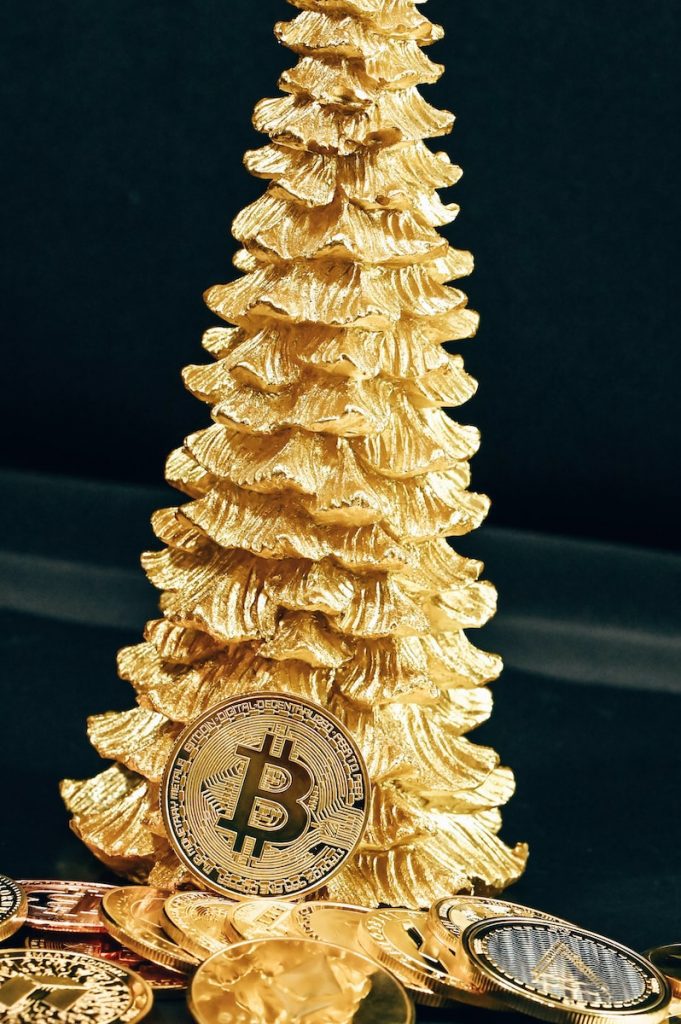 a gold christmas tree with bitcoin coins around it